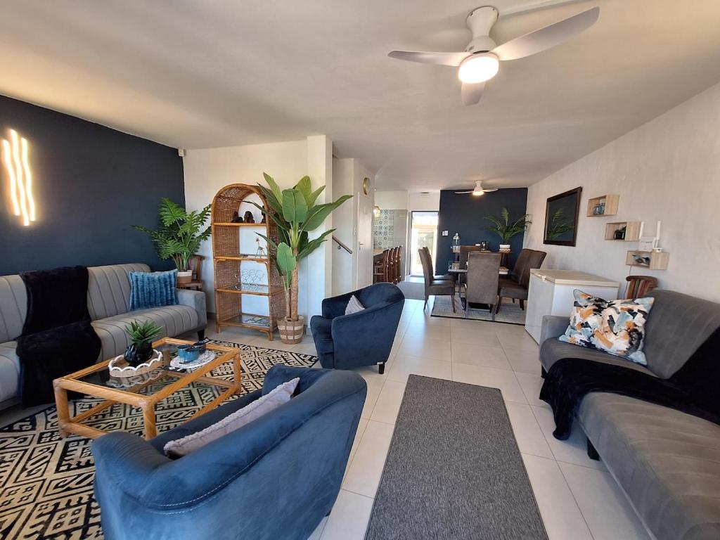 a living room with blue furniture and a ceiling fan at The Wave House on the Beach in Port Alfred