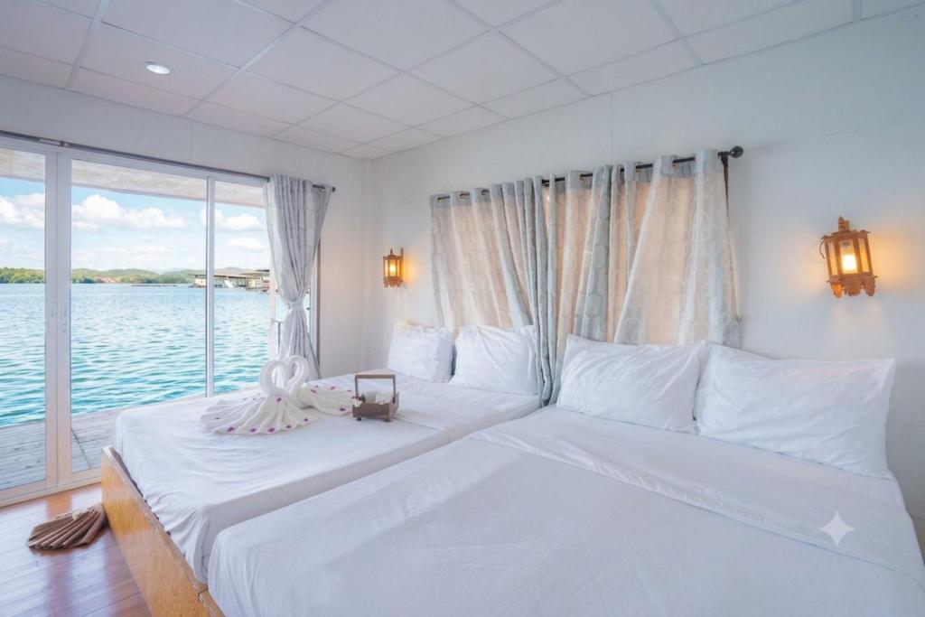 a white bed in a room with a large window at Phupai Lake Resort in Ban Wang Khun Knachen
