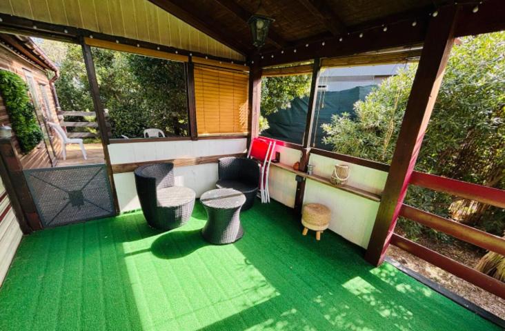a screened in porch of a house with a green floor at La cabane Proche circuit in Le Castellet
