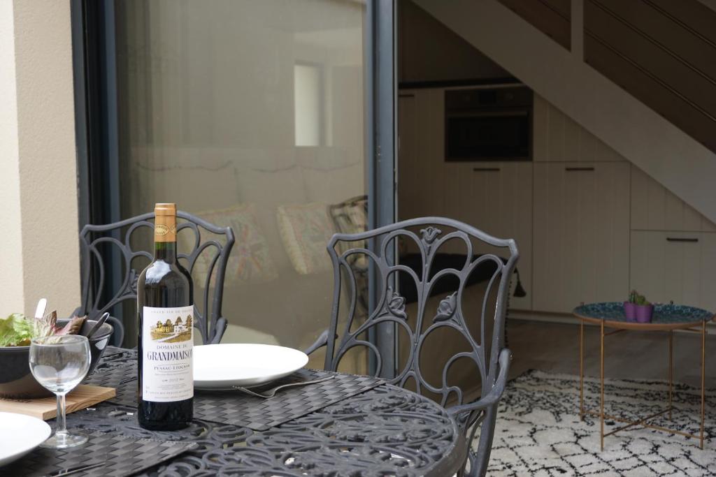 La Villa Verte في بوردو: زجاجة من النبيذ موضوعة على طاولة مع كراسي