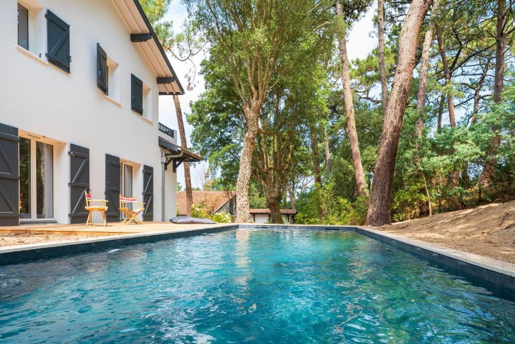 a swimming pool in front of a house with trees at Villa proche du lac d'Hossegor in Soorts-Hossegor