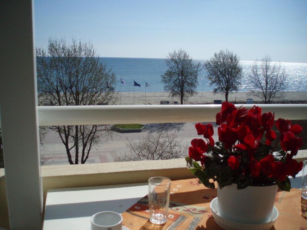 a vase of flowers on a table with a view of the beach at Giorgos Apartments Sea View in Olympiaki Akti