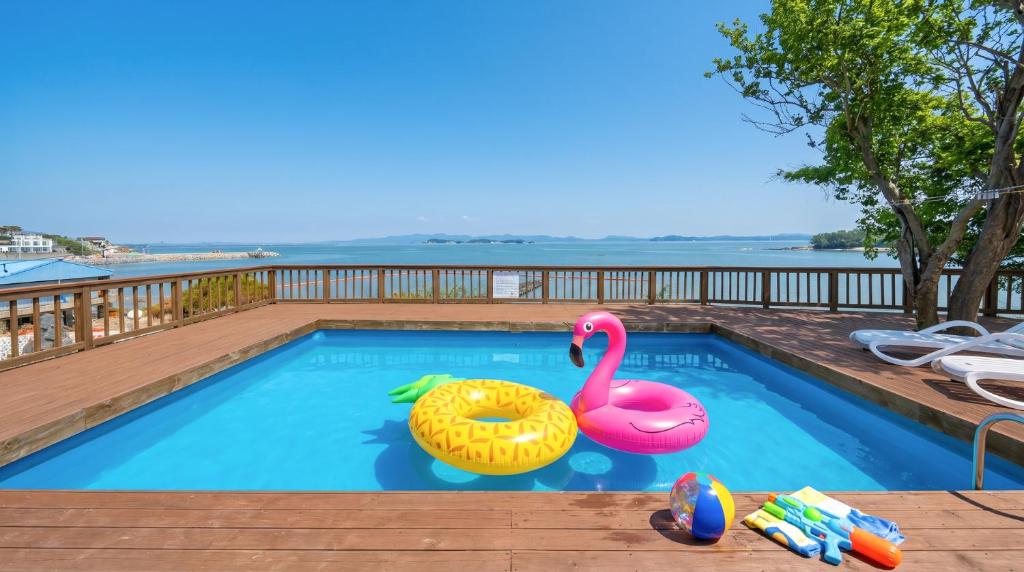 a swimming pool with a pink swan and a float at Taean Tteulapbada Pension in Taean