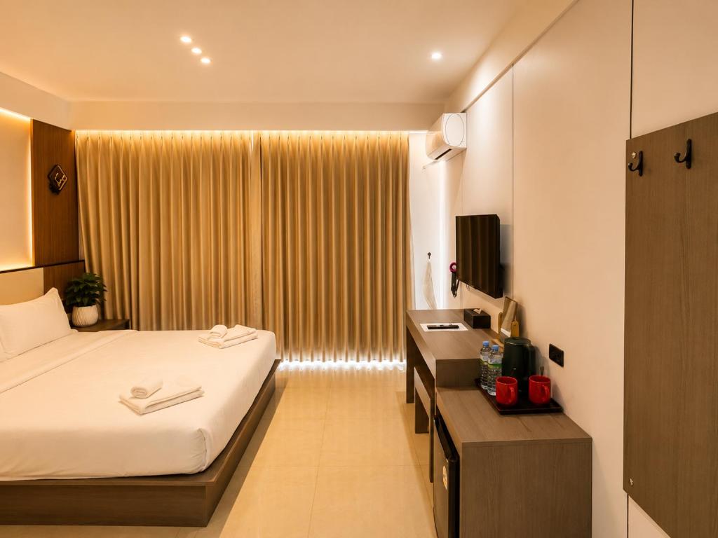a bedroom with a bed and a desk and a window at Happy Room 3 in Pattaya South