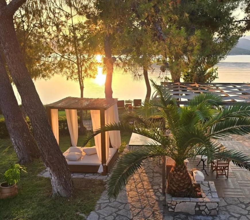 a gazebo and a palm tree with the sunset at Flisvos Seaside Apartments in Lygia