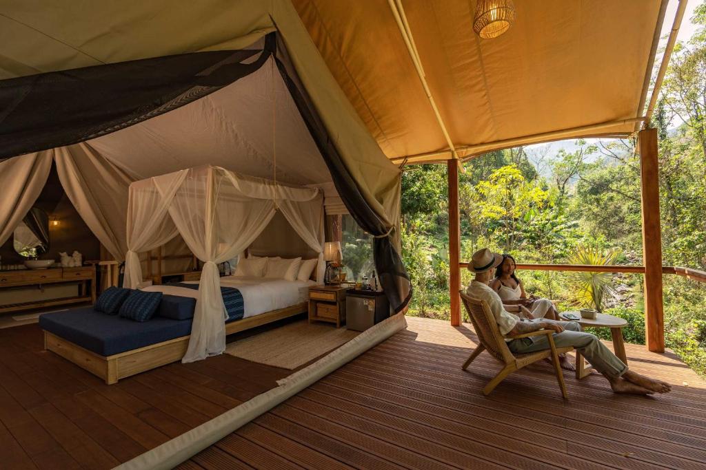 a couple sitting in a bed in a tent at Visama Explorer Nan in Ban Huai Luk