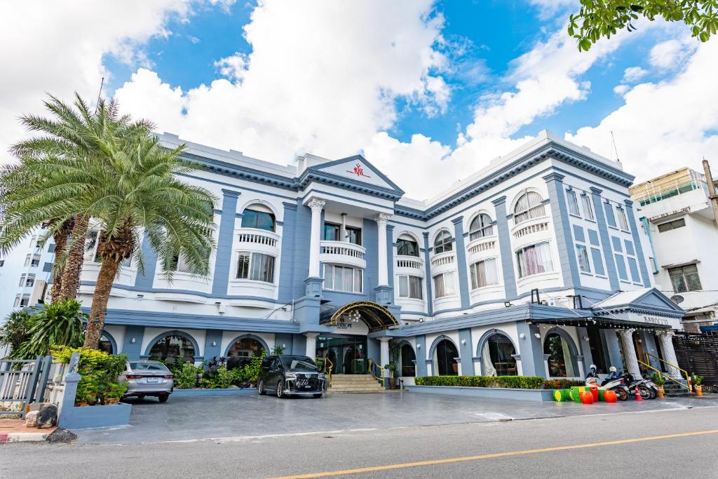 a large building with a palm tree in front of it at Kiss Gardenhome Chic Hotel in Hat Yai