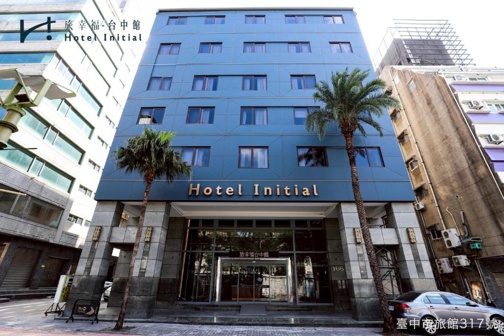 a blue hotel with palm trees in front of it at Hotel Initial-Taichung in Taichung