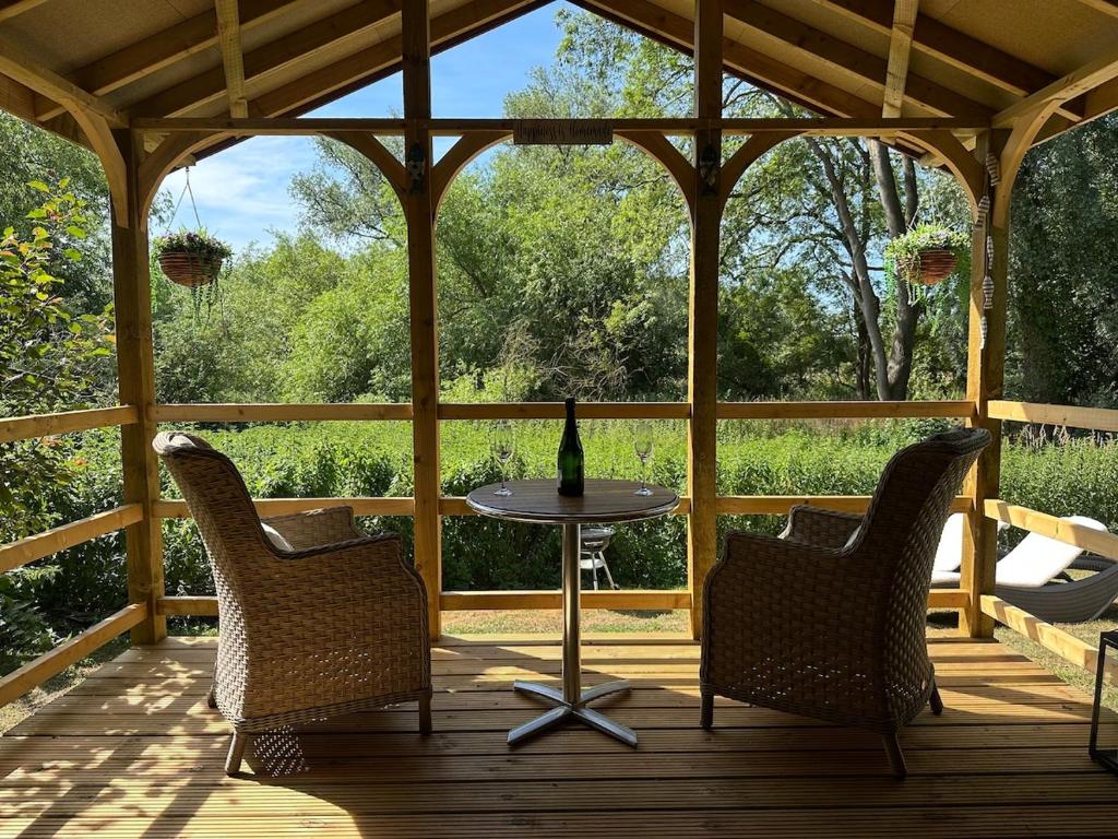 two chairs and a table on a wooden porch at Woody Nook Annexe in Pavenham
