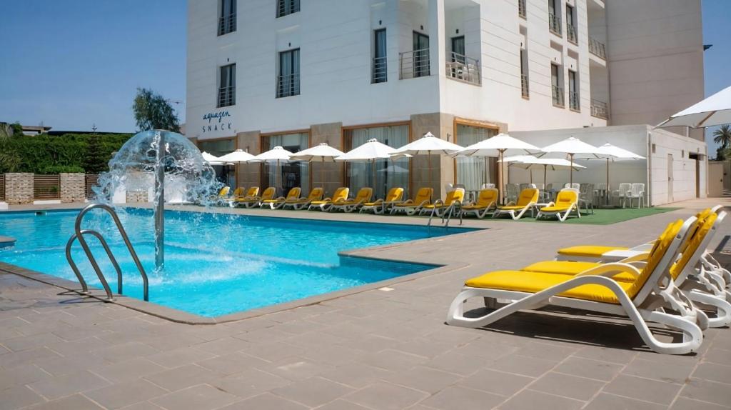 ein Schwimmbecken mit Liegestühlen und einem Springbrunnen in der Unterkunft Hotel Zenith in Oran