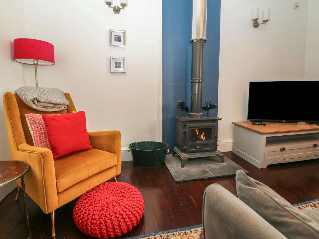 a living room with a chair and a fireplace at Cosy Cottage in Buxton