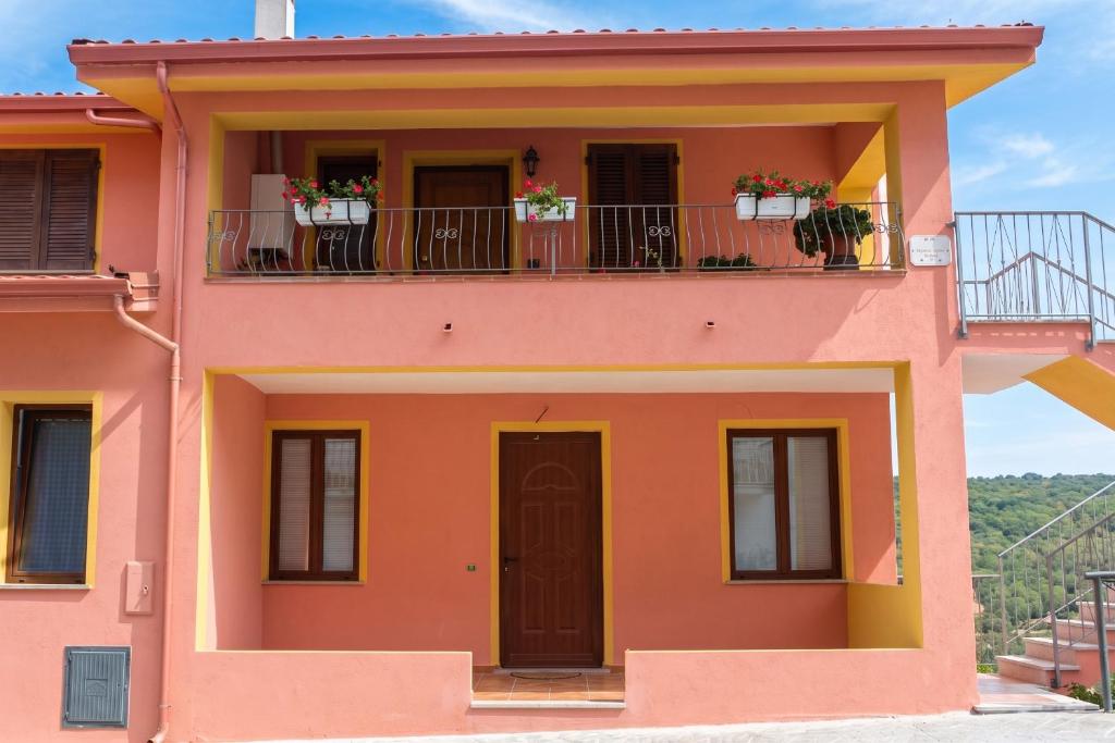 a pink house with flowers on the balcony at Charming apartment in Nughedu Santa Vittoria - 90 m² with fireplace in Nughedu Santa Vittoria