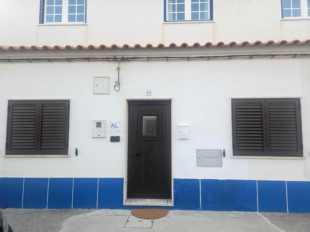 a white building with a door and two windows at Casa Saudade Beach House in Zambujeira do Mar