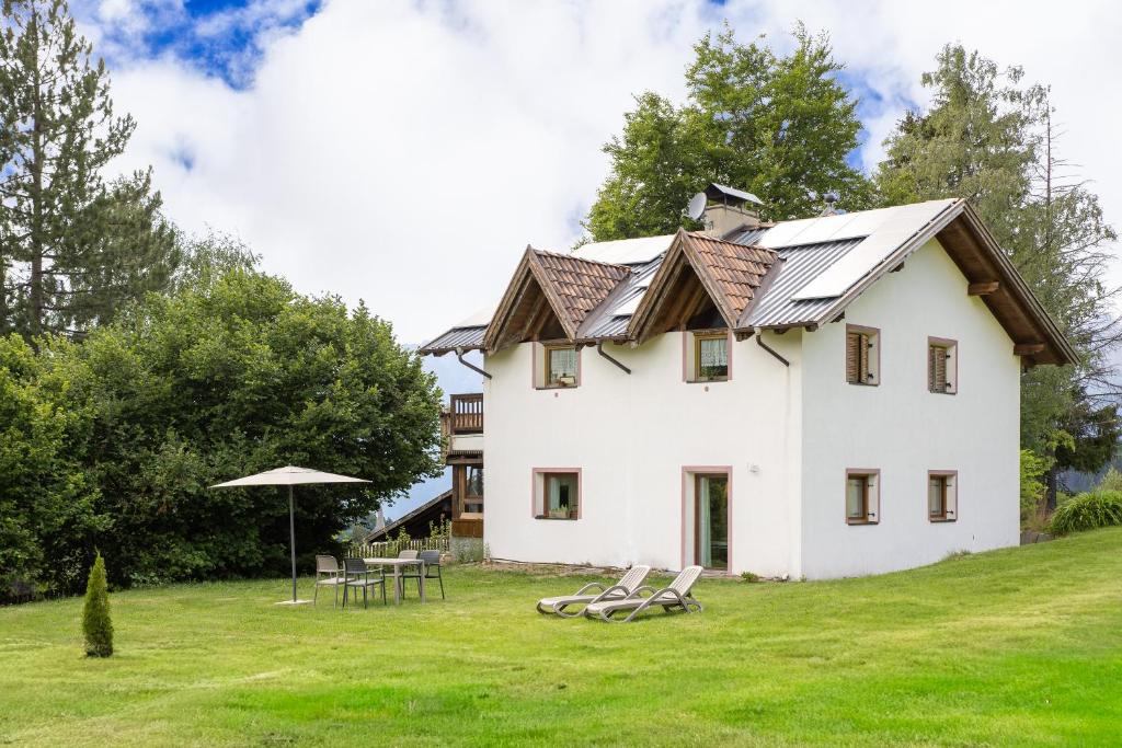 a house on a hill with chairs and an umbrella at Apartments Schießstand in Avelengo