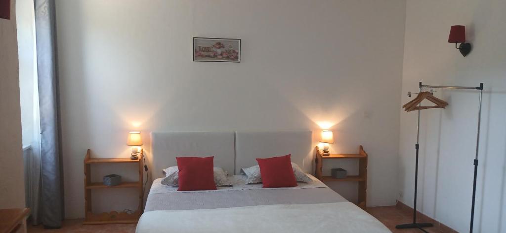 a bedroom with a bed with red pillows and two lamps at E I PERLES de AIME in Laurac-en-Vivarais