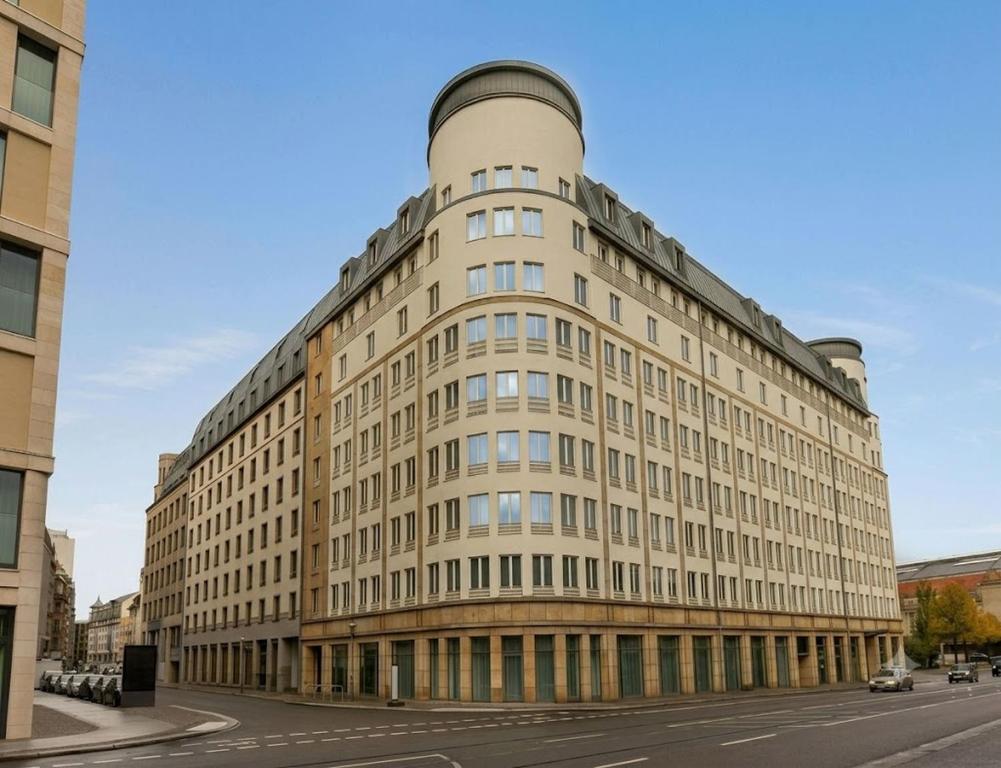 a large building with a round top on a street at Sunday Hotel Leipzig in Leipzig