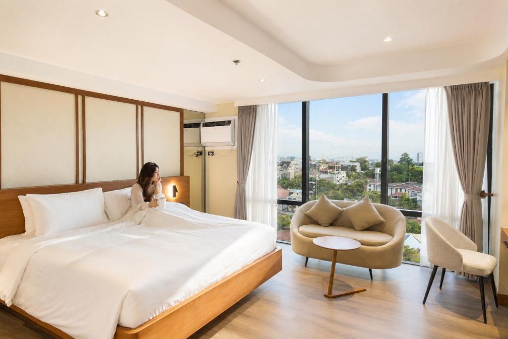 a woman sitting on a bed in a hotel room at oneTree Plaza Hotel Cebu in Cebu City