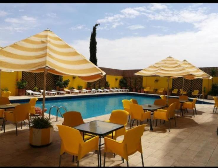 a pool with tables and chairs and umbrellas at Mariam Hotel in Madaba