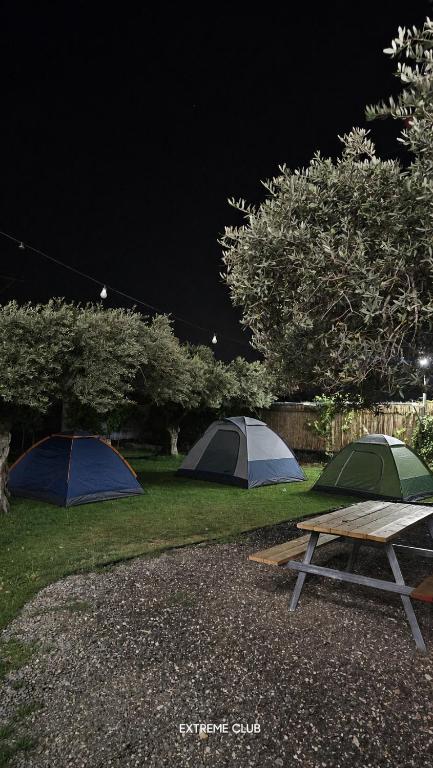 a picnic table and two tents in a field at night at extreme park in Deir Ḥannā