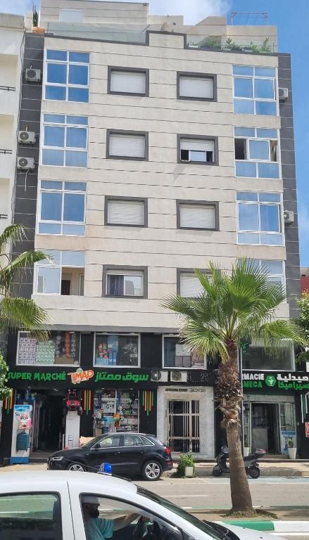 a tall building with a palm tree in front of it at appart plage in M'diq