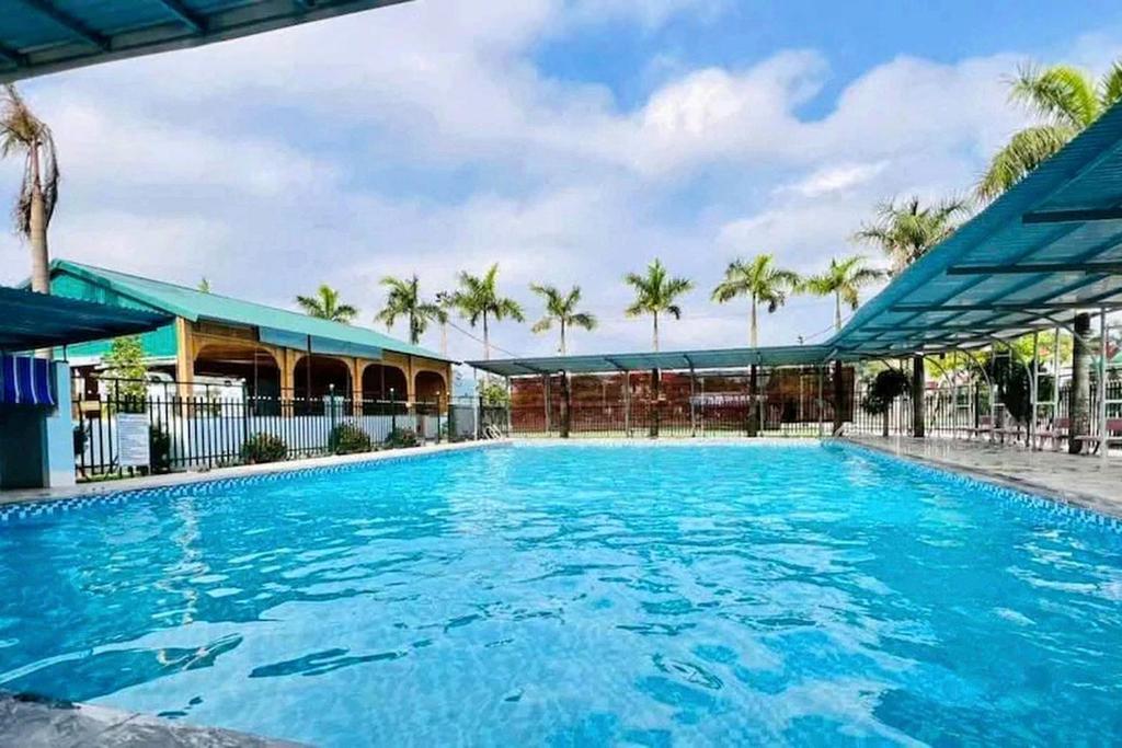 a large blue swimming pool with palm trees in the background at Palette Sunset Garden Tam Coc in Ninh Binh