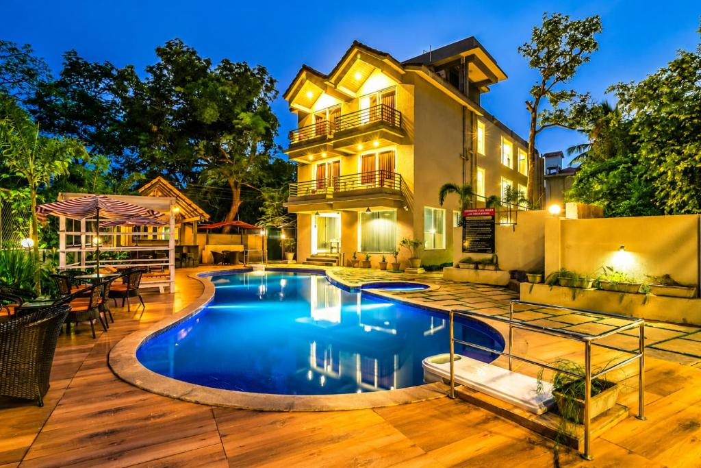 a house with a swimming pool in front of a house at Ramatan Resort in Vagator