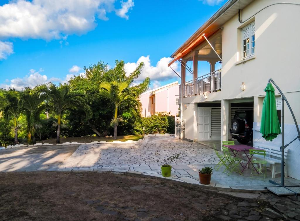 a house with a patio and a green umbrella at Studio charmant à Rivière Salée - 22 m² + Parking in Rivière-Salée