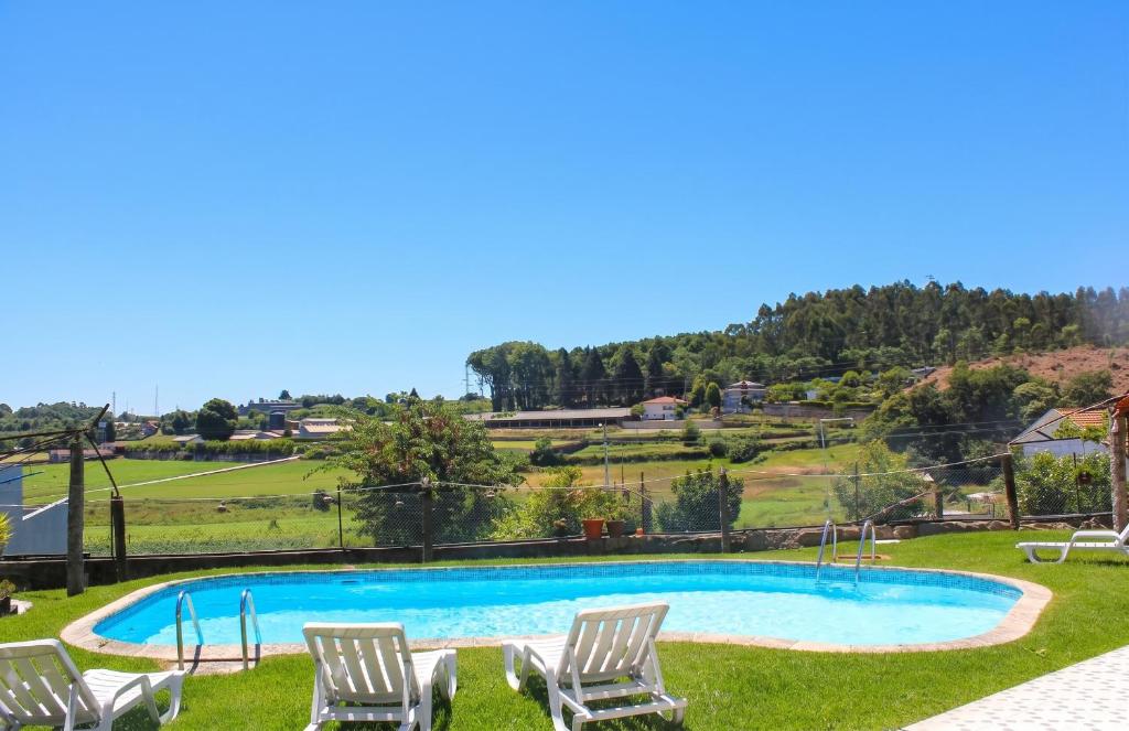 a swimming pool with chairs and a hill in the background at Charming House in Requião with Shared Pool in Requião