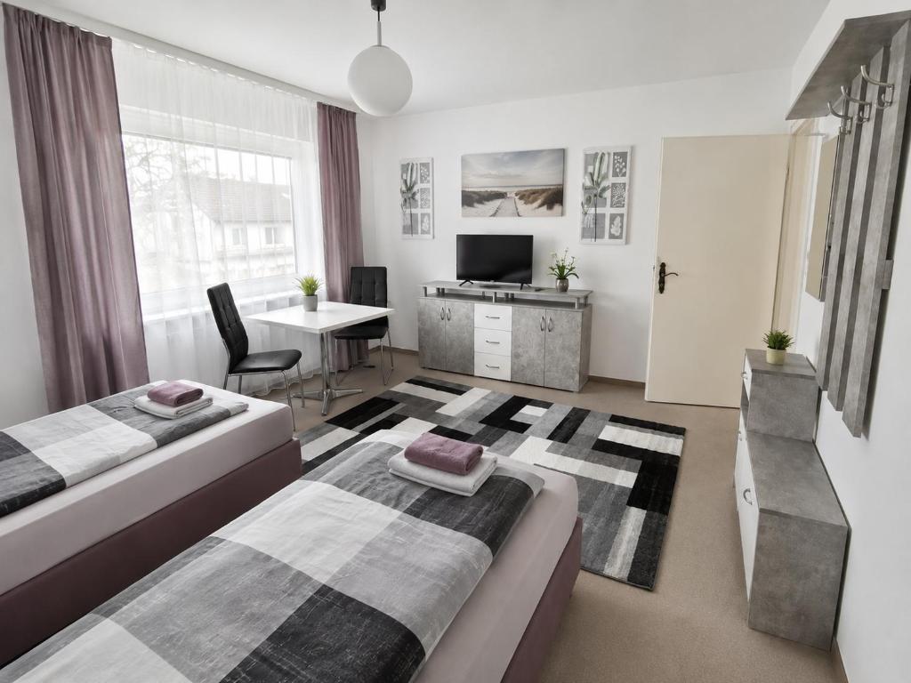 a bedroom with two beds and a desk and a tv at M&M Apartments in Augustdorf
