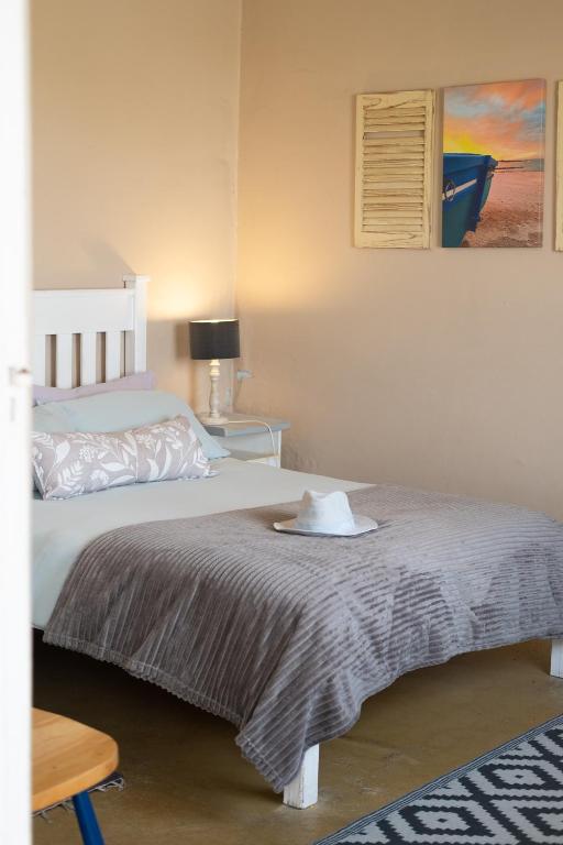 a bedroom with a bed with a blanket on it at Haus Windhoek - Charming Coastal Escape in Struisbaai