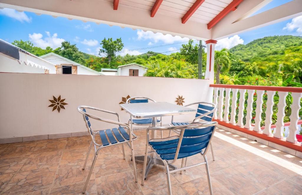 a patio with a table and chairs on a balcony at Maison vue sur mer à Vieux-Habitants + Terrasse in Vieux-Habitants