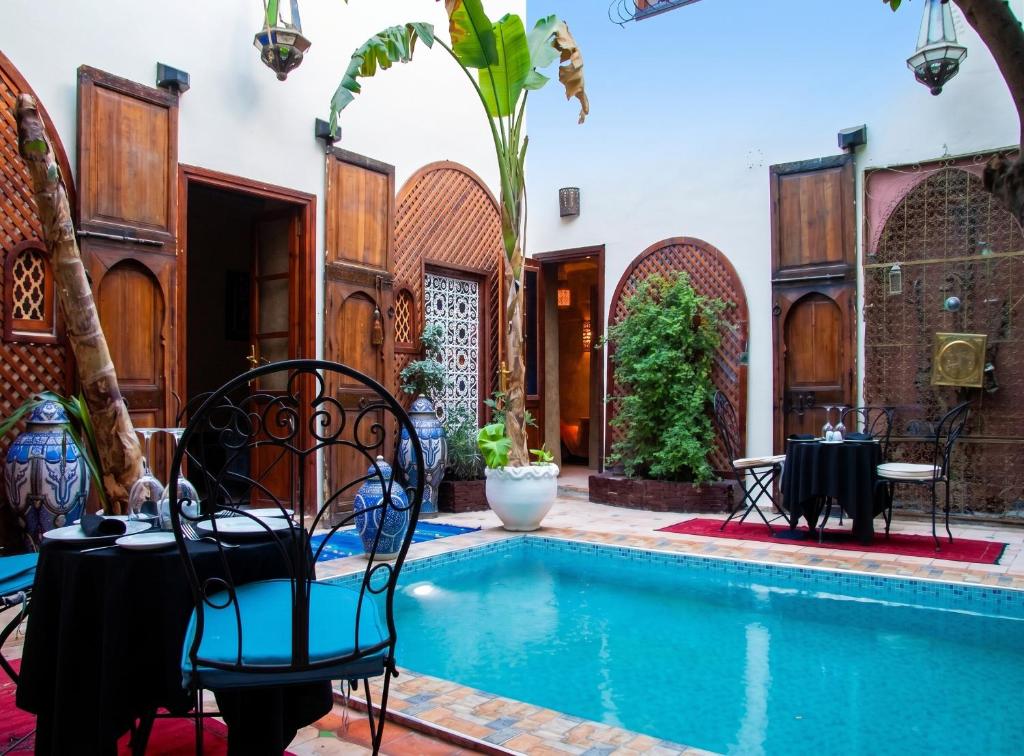a pool with tables and chairs next to a house at Exceptional Villa in Marrakech with Private Pool in Marrakesh