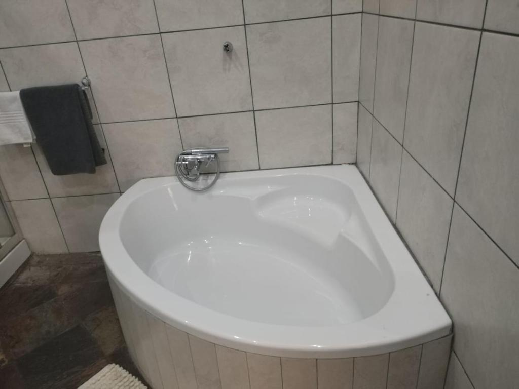 a white toilet in a tiled bathroom with a sink at Unitas Park B&B in Vereeniging