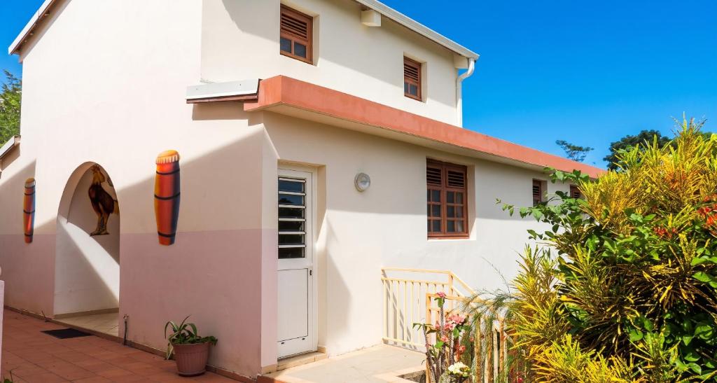 a white house with a door and a fence at Appartement accueillant au Robert avec balcon et jardin in Le Robert