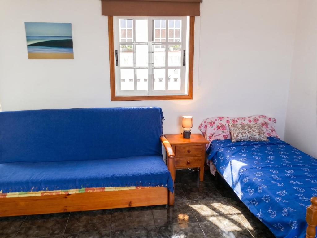 a bedroom with a blue couch and a bed and a window at Cosy Studio with Sea View and Garden in Frontera - 20 m² in Frontera