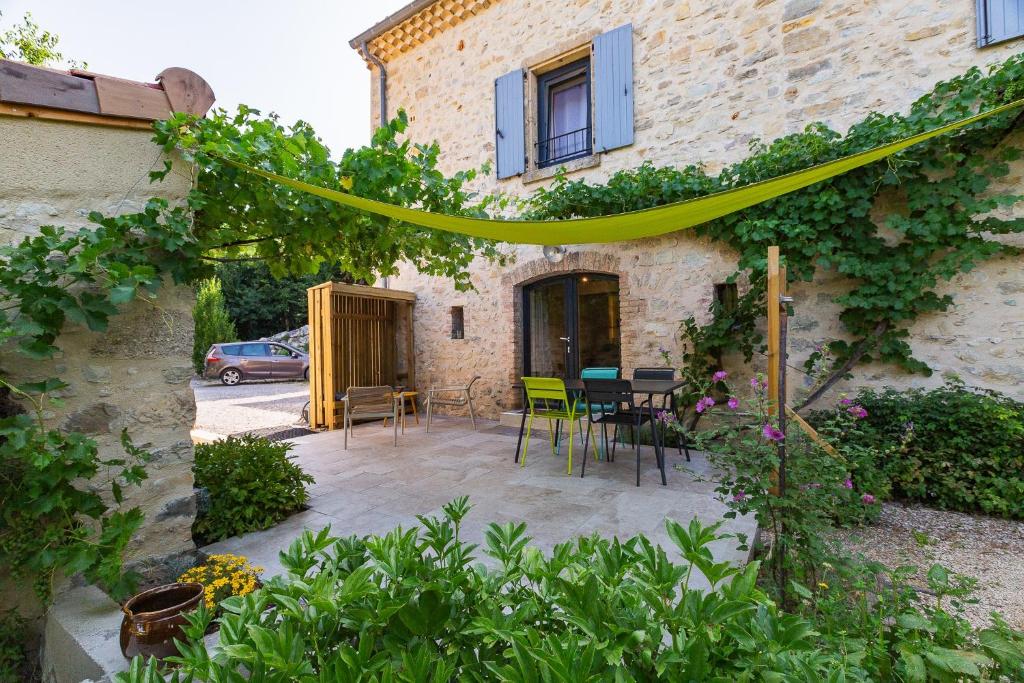 a patio with a table and chairs in front of a building at Gîte La Peyrolle in Aouste-sur-Sye