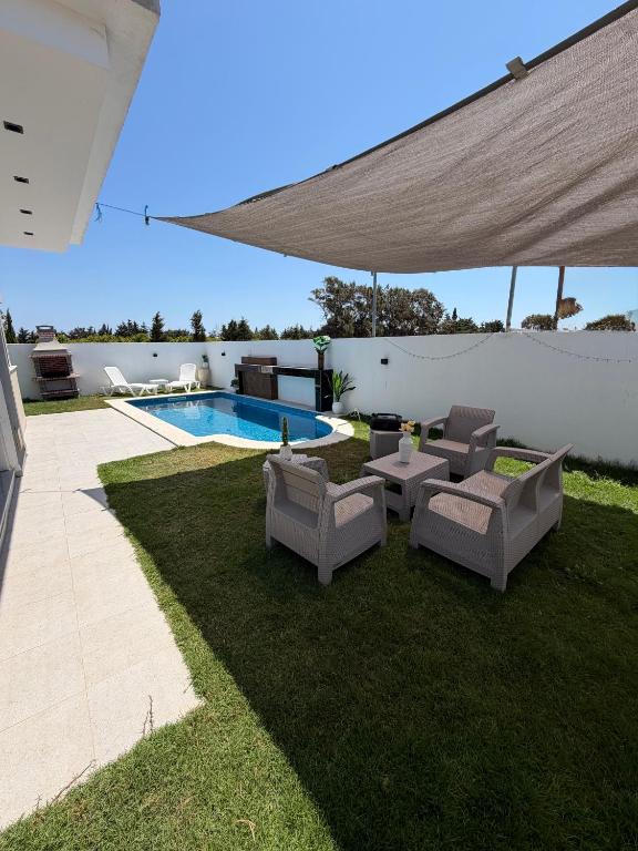 a patio with two chairs and a table and a pool at Villa Luna in Hennchir Ksar Rhaleb