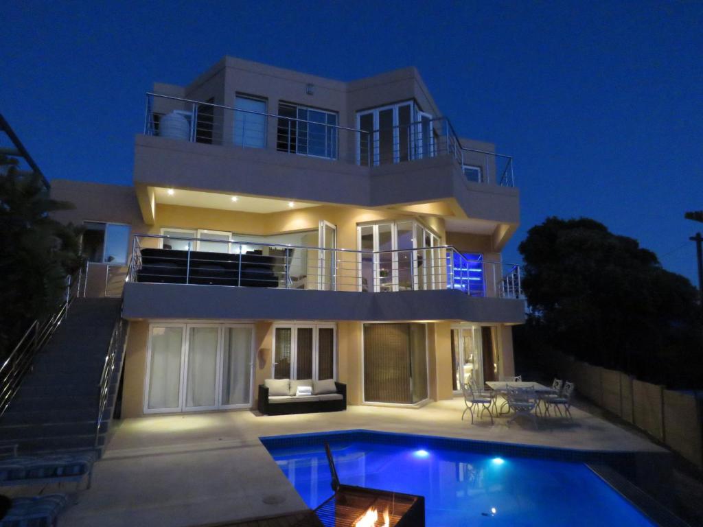 a large house with a swimming pool in front of it at Gull on the Bay Boutique Guest House in Bloubergstrand