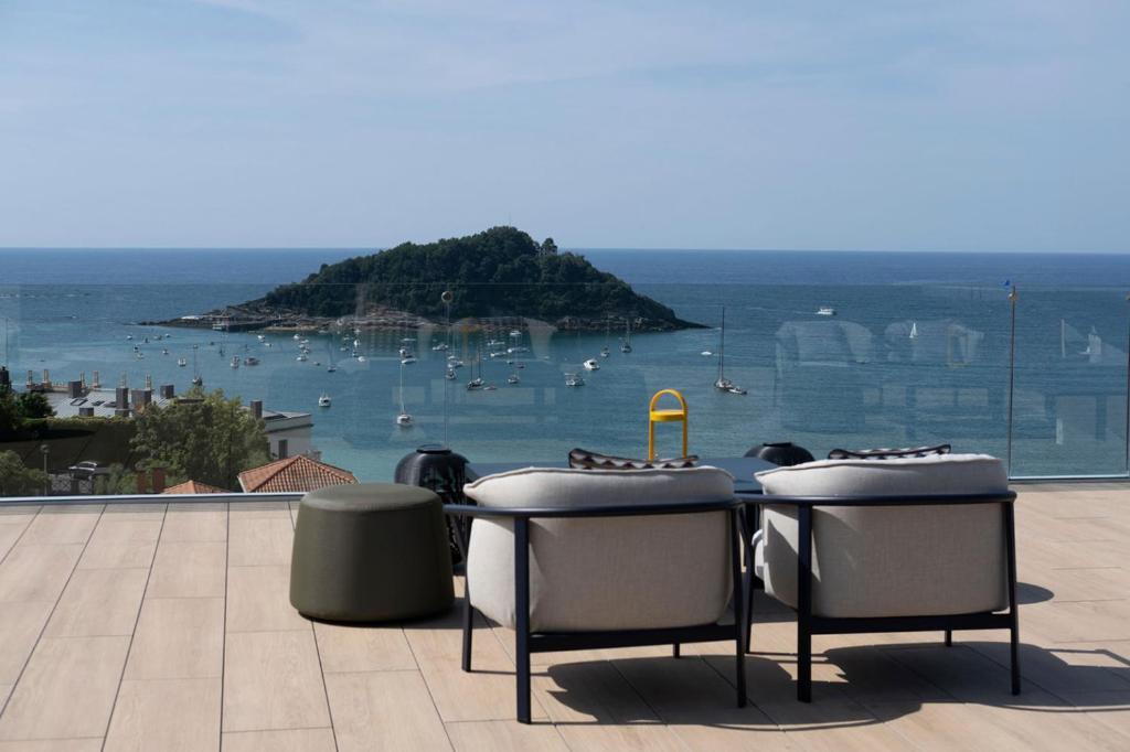 a table and two stools on a balcony with an island at Eurostars Villa Itziar in San Sebastián
