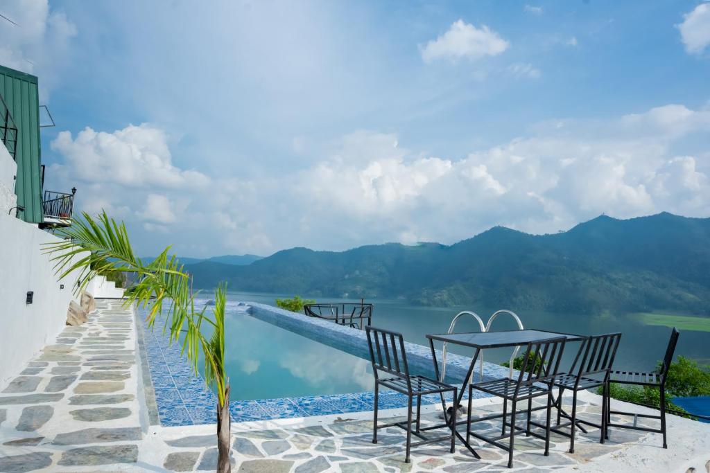 a table and chairs on a patio with a view of the water at The Edge Villa & Retreat in Pokhara