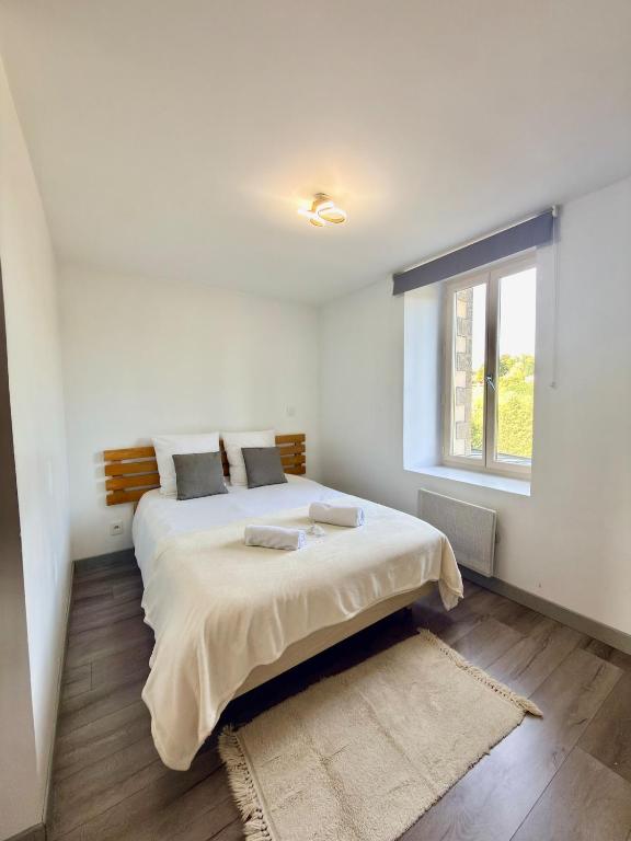 a white bedroom with a large bed with a window at T2 calme rue Pasteur appartement 1 - DABNB in Le Palais-sur-Vienne