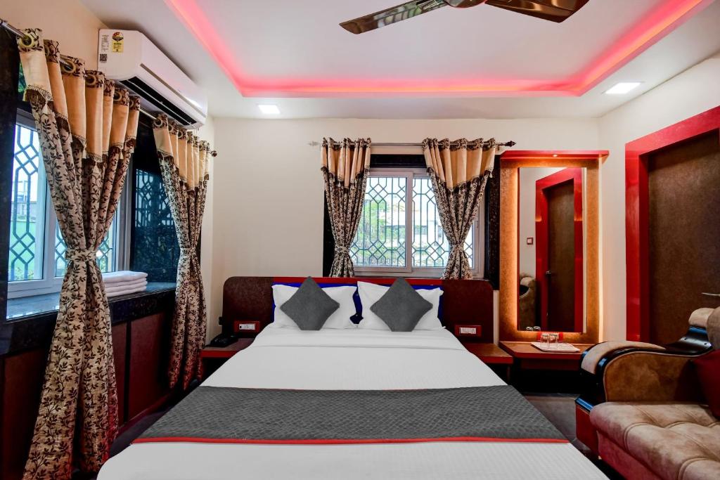 a bedroom with a bed and a couch and windows at Hotel O THE CROWN COMFORTS in Kolkata