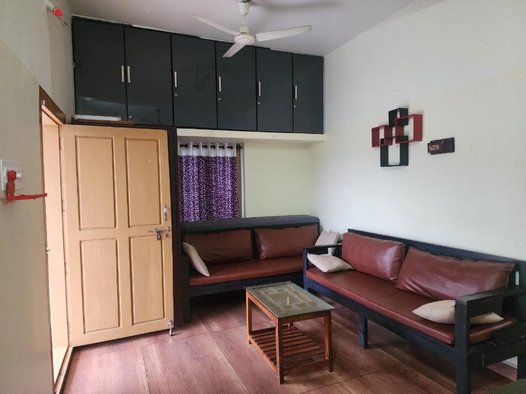 a living room with two leather couches and a door at Mount View Attappadi in Agali