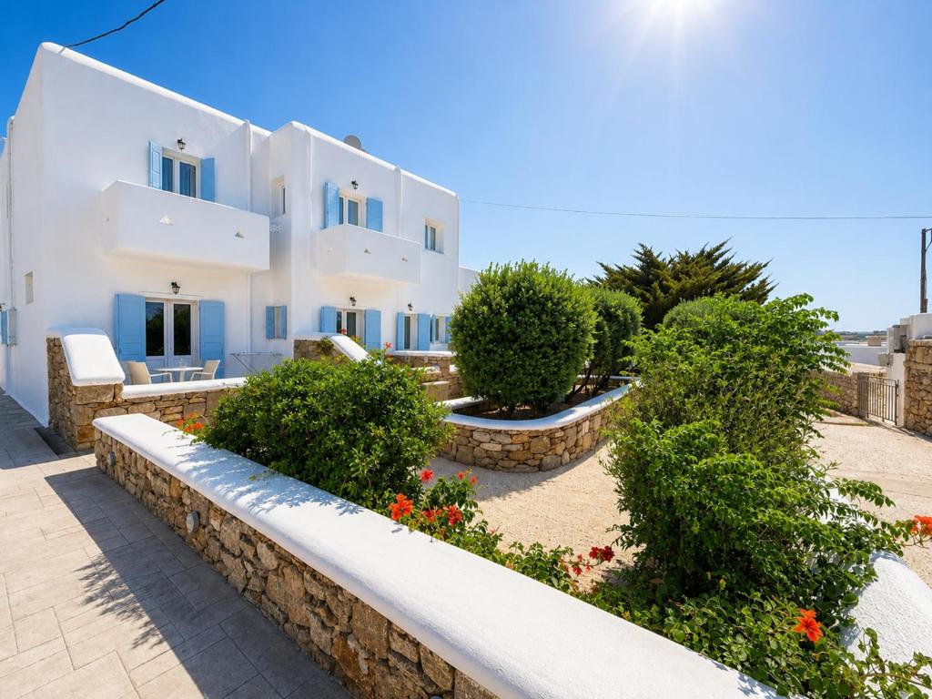 a large white building with a stone wall at Eleftheria Hotel & Apartments in Ornos