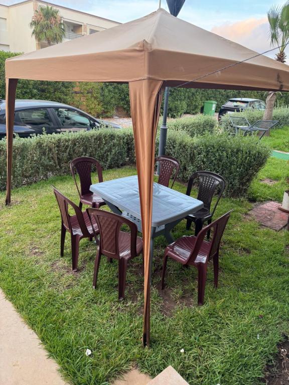 a table and chairs under an umbrella in the grass at Villa Savannah Beach in Sidi Rahal