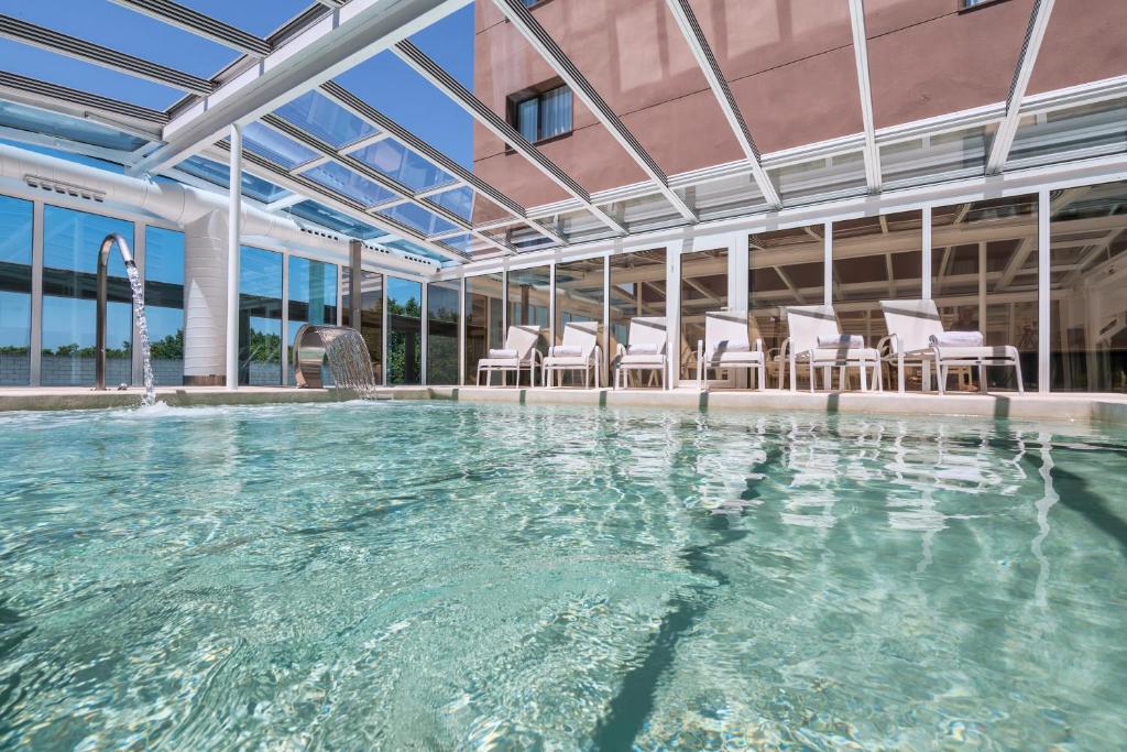 a swimming pool with chairs in a building at Salles Ciutat del Prat Barcelona Airport in El Prat de Llobregat