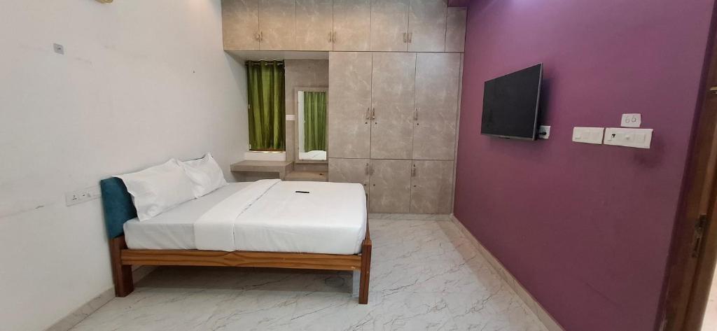a bedroom with a bed and a purple wall at The Green stays in Madurai