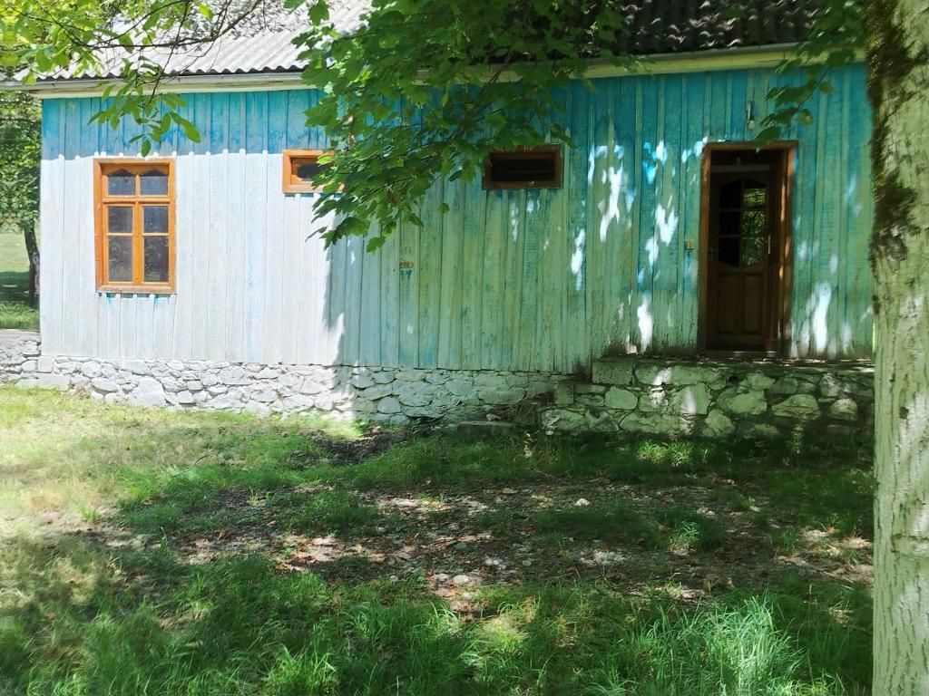 a blue house with a stone wall and a door at Gurbanefendi forest cottages in Qurbanǝfǝndi