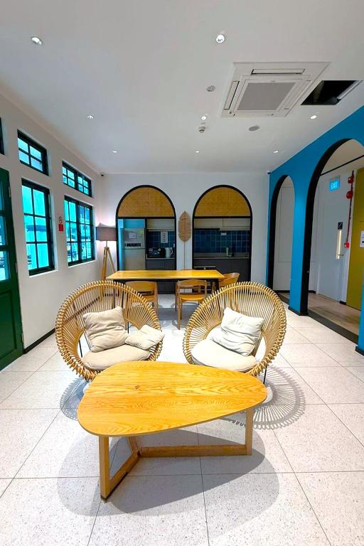 a living room with three chairs and a table at GoStay Pods at Perak Road in Singapore