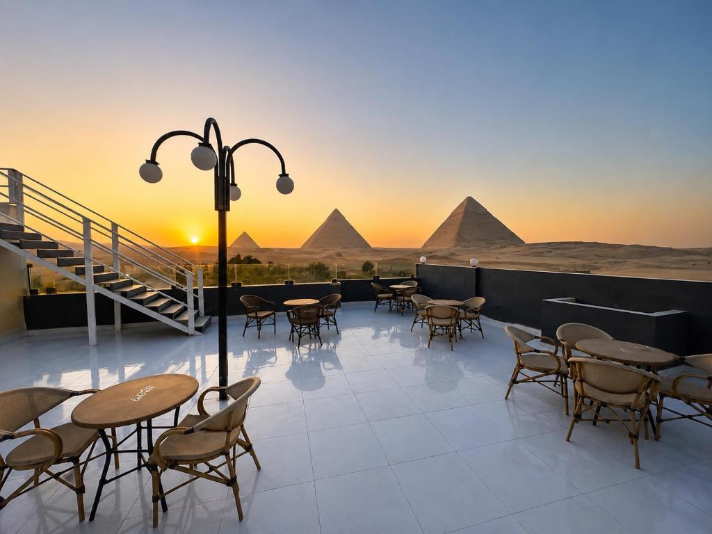 a patio with tables and chairs with pyramids in the background at Prince Pyramid HoteLL in Cairo